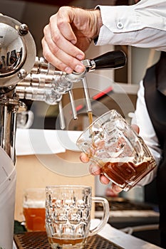 Bartender hands pouring a draught craft beer into a mug