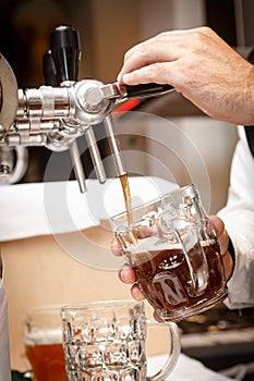 Bartender hands pouring a draught craft beer into a mug