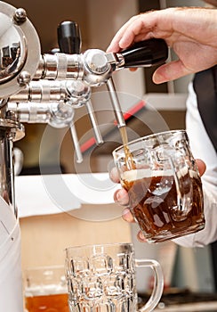 Bartender hands pouring a draught craft beer into a mug