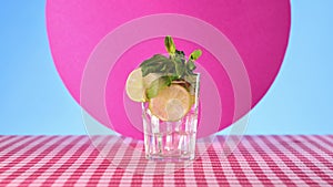 Bartender making alcohol Mojito cocktail on checkered tablecloth over abstract colorful background. Decorated with fresh