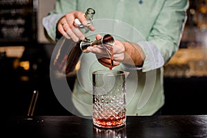 Bartender making alcoholic cocktail , metal jigger and bar environment