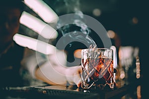 bartender making cocktail in bar with smoke