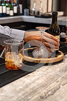 Bartender making smoked whiskey cocktail drink with glass beaker and upside down cocktail glass