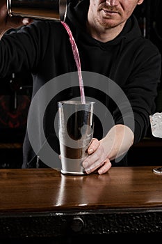 Bartender mixes egg white, lemon, dry vermouth and gin to prepare the Clover club cocktail. Barman prepares classical