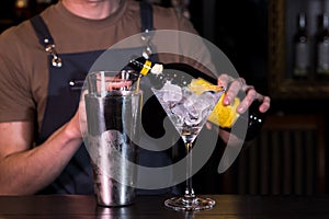 The bartender at the nightclub behind the bar making an Espresso Martini cocktail.