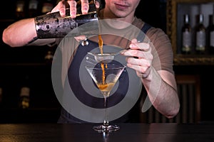 The bartender at the nightclub behind the bar making an Espresso Martini cocktail.