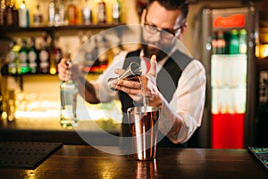 Bartender pouring alcohol beverage in metal glass