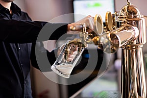 Bartender pouring beer from faucet in pint glass