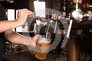 Bartender pouring beer from tap into glass in bar