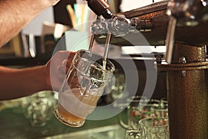 Bartender pouring beer from tap into glass in bar