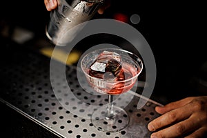 Bartender pouring campari liquor from shaker into the cocktail glass