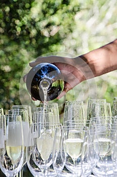 Bartender pouring champagne into wine glasses at outdoors celebration