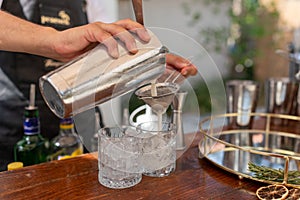 Bartender pouring a cocktail in a cup