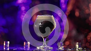 Bartender pouring cool dark beer or soda in glass on bar counter in nightclub, closeup view, slowmo