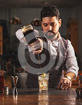 Bartender pouring craft cocktail at bar