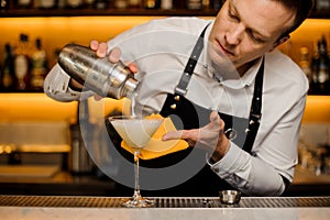 Bartender pouring a fresh alcoholic drink into the cocktail glass