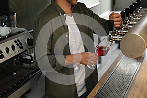 Bartender pouring fresh beer into glass in pub