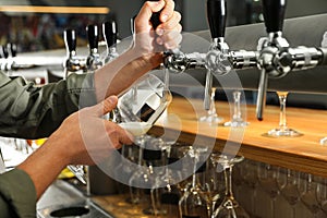 Bartender pouring fresh beer into glass in pub