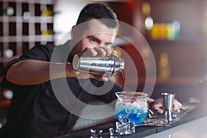 Bartender pouring fresh cocktail in fancy glass.