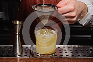 Bartender pouring fresh cocktail in fancy glass