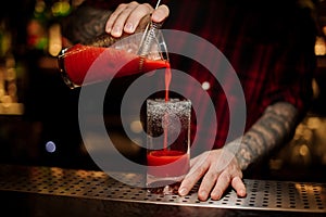 Bartender pouring fresh salty tomato alcoholic drink into a glass