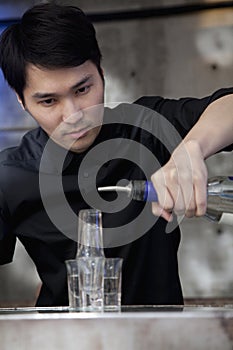 Bartender pouring licour on shot glass pyramid