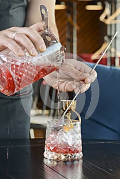 Bartender pouring liquid in a cocktail drink. Summer alcohol drink in a restaurant or bar. Barman at work.