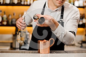 Bartender pouring a portion of alcoholic drink into a cup