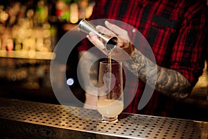 Bartender pouring a portion of alcoholic drink using jigger