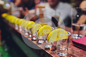 Bartender pouring strong alcoholic drink into small glasses on bar, shots. photo