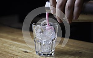 Bartender pouring a strong alcoholic drink into small glasses with ice. Red alcoholic drink. Barman is preparing a cocktail