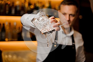 Bartender pouring water from a glass with ice cubes