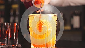 Bartender pours syrup in exotic fruit cocktail