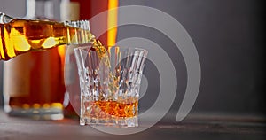 bartender pours whiskey into a glass goblet against the background of bottles