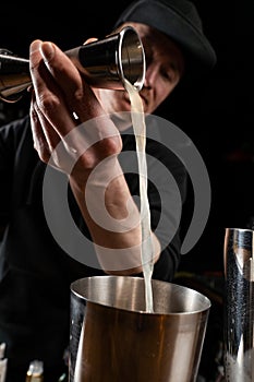 Bartender prepares classical Clover club alcoholic cocktail at the bar. Bartender mixes egg white, lemon, dry vermouth