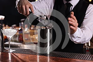 Bartender preparing fresh alcoholic cocktail at bar counter, closeup