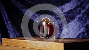 Bartender putting cherry into negroni cocktail. Dark background. Gin, sweet vermouth, red Campari bitter liqueur