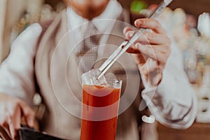 Bartender putting ice into a bloody marry drink