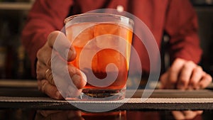 Bartender serves a Negroni cocktail on the bar counter