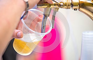 A bartender serving beer at a dispenser in plastic glasses