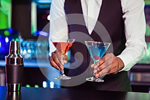 Bartender serving blue and orange cocktail drinks