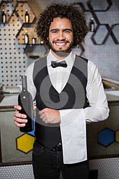 Bartender serving bottle of wine in bar counter