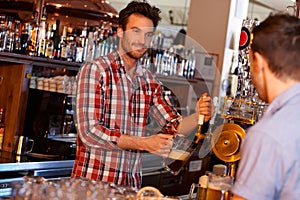 Bartender serving draught beer in bar