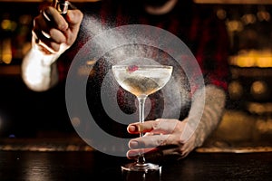 Bartender sprinkling bitter on the elegant cocktail glass