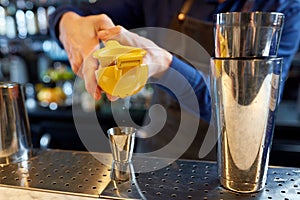 Bartender squeezing juice into jigger at bar