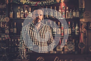 Bartender standing at bar counter in his pub.