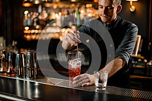 Bartender stirring alcohol drink with a bar spoon