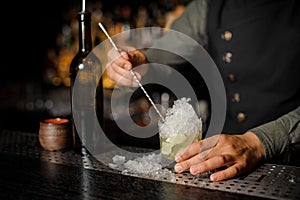 Bartender stirring cachaca with lime and ice making Caipirinha c