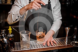 Bartender stirring cocktail in the ornate glass on the bar counter