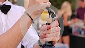 The bartender is taking out a stopper from a bottle.